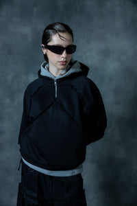 Woman wearing black cotton zip neck hoodie with layered hood and minimal streetwear design in modern portrait style