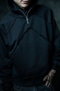 Close up of premium black zip neck hoodie showcasing raw edges and minimal streetwear design