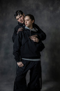 Couple wearing black zip neck hoodies styled in modern unisex streetwear look with relaxed fit