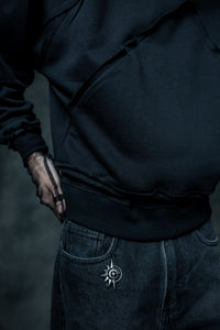 Close up of black zip neck hoodie highlighting raw edge hem detailing and premium streetwear construction