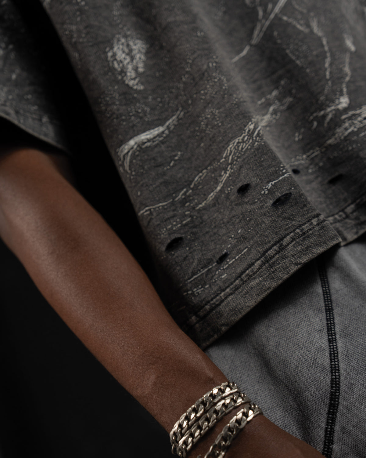 Close-up macro detail of the distressed hem finishing on a washed charcoal oversized t-shirt