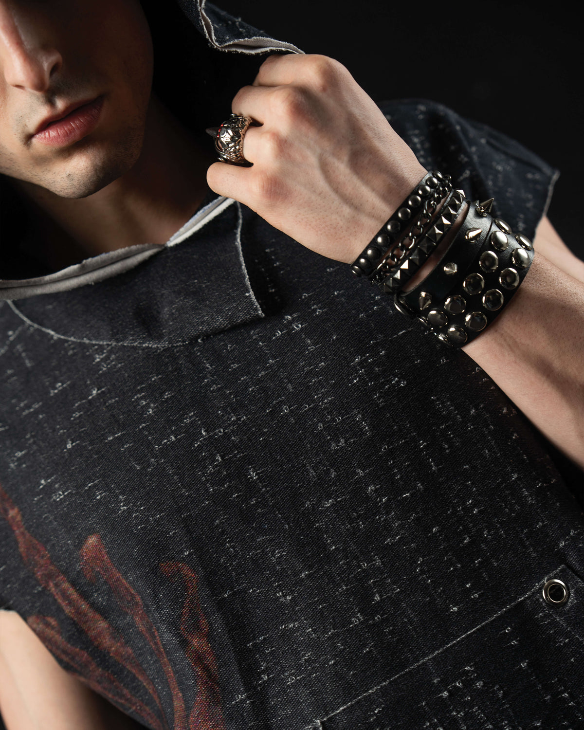 Detail shot of layered metal accessories paired with a washed charcoal oversized graphic hooded tee