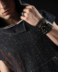 Detail shot of layered metal accessories paired with a washed charcoal oversized graphic hooded tee