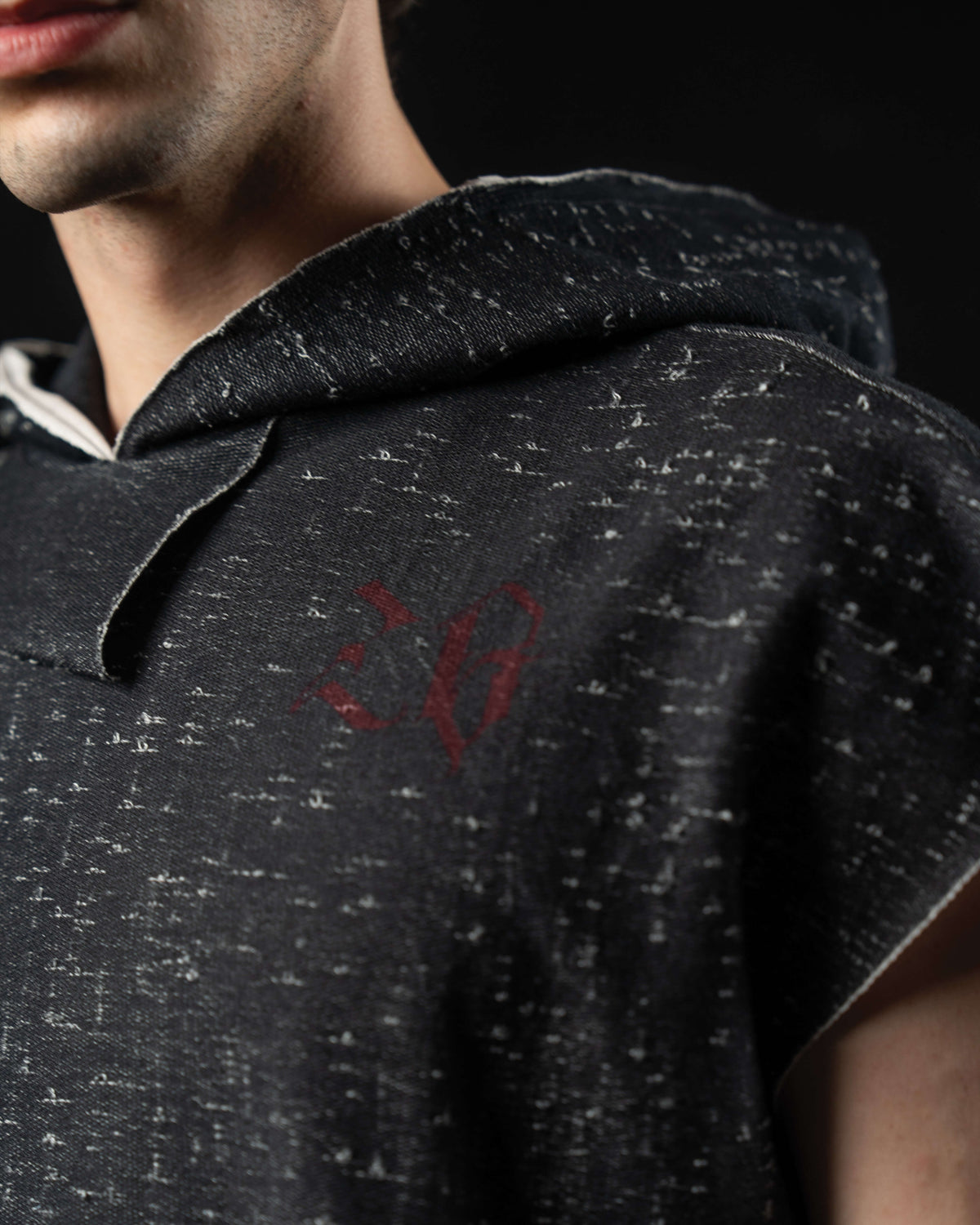 Close-up of the distressed charcoal fabric and subtle gothic chest logo on a hooded graphic tee