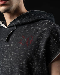 Close-up of the distressed charcoal fabric and subtle gothic chest logo on a hooded graphic tee