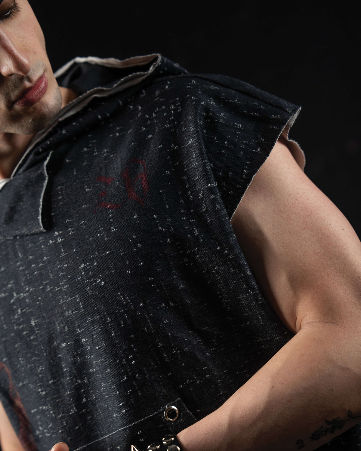 Close-up sleeve detail of a washed charcoal oversized hooded graphic tee featuring raw-cut edges