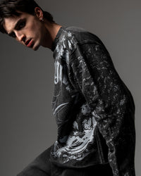 Left-side profile shot of a model wearing a washed charcoal oversized graphic long sleeve tee showing the vintage texture