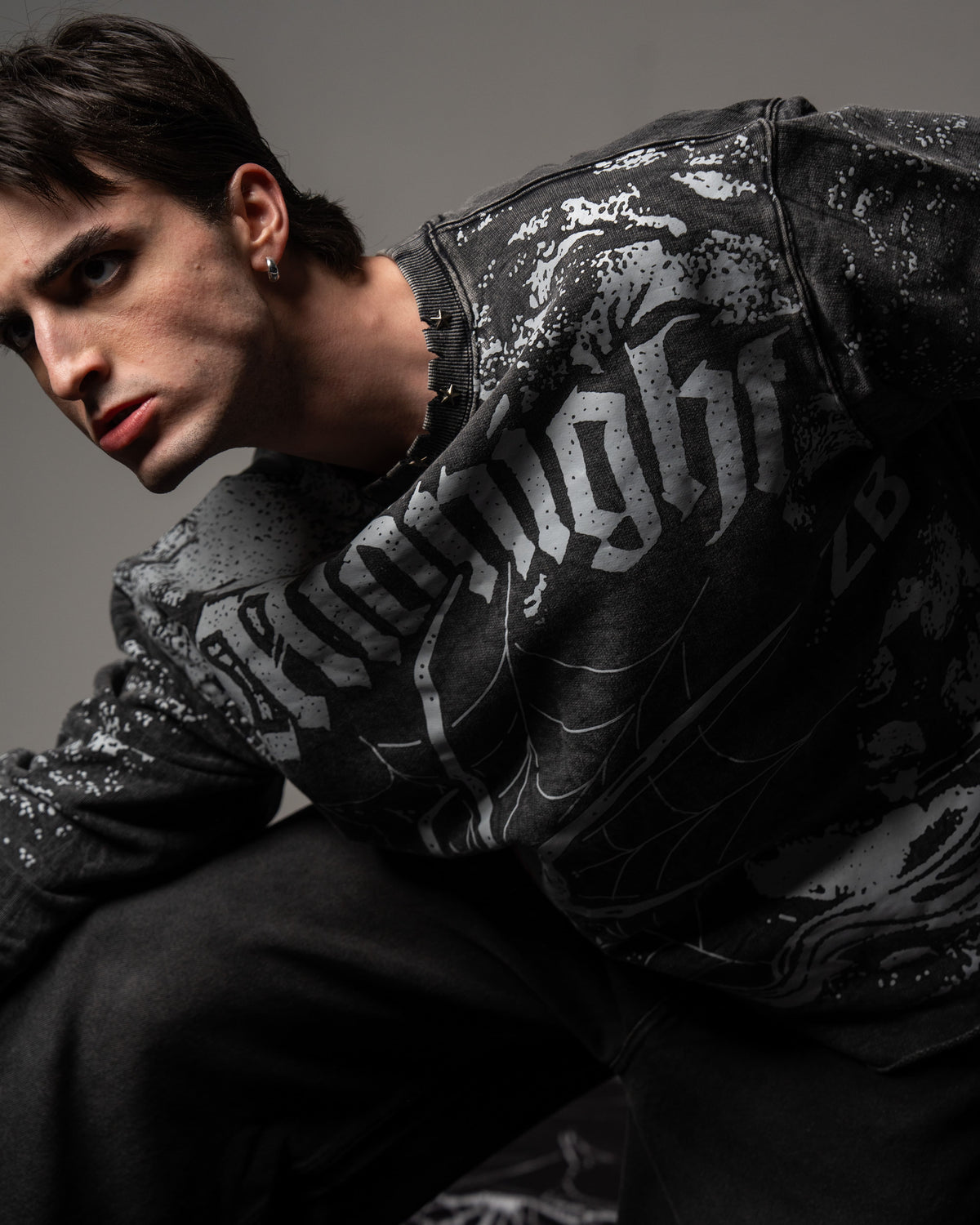 Side profile portrait showcasing the sleeve graphics on a vintage washed charcoal oversized spiderweb long sleeve tee