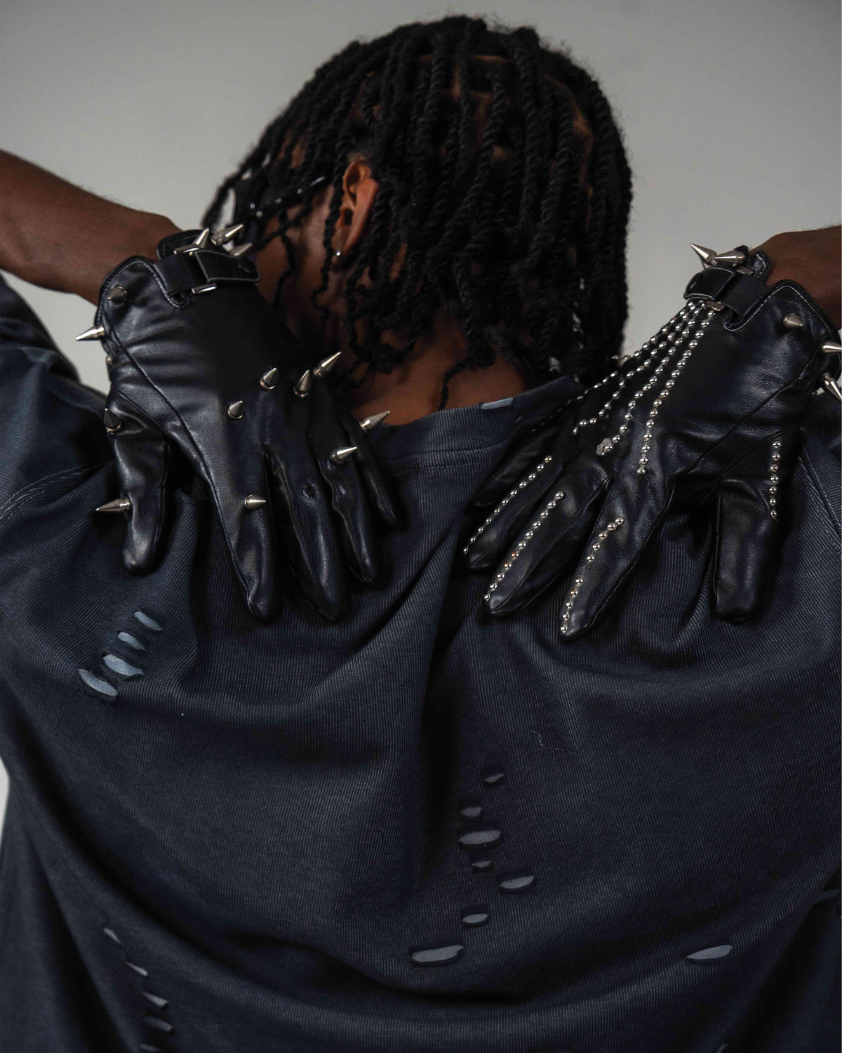 Back detail view of oversized distressed black t-shirt with black gloves