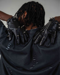 Back detail view of oversized distressed black t-shirt with black gloves
