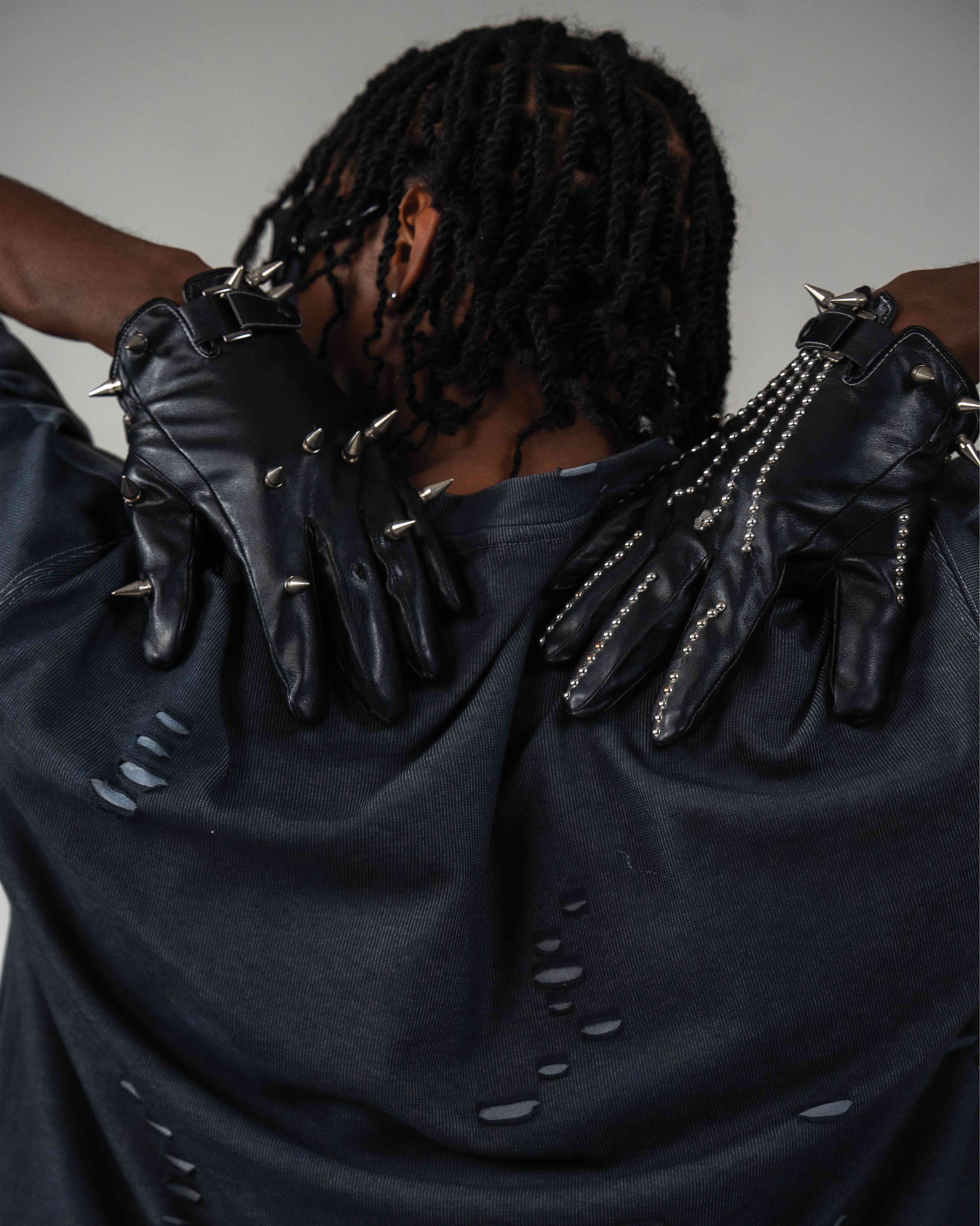 Back detail view of oversized distressed black t-shirt with black gloves