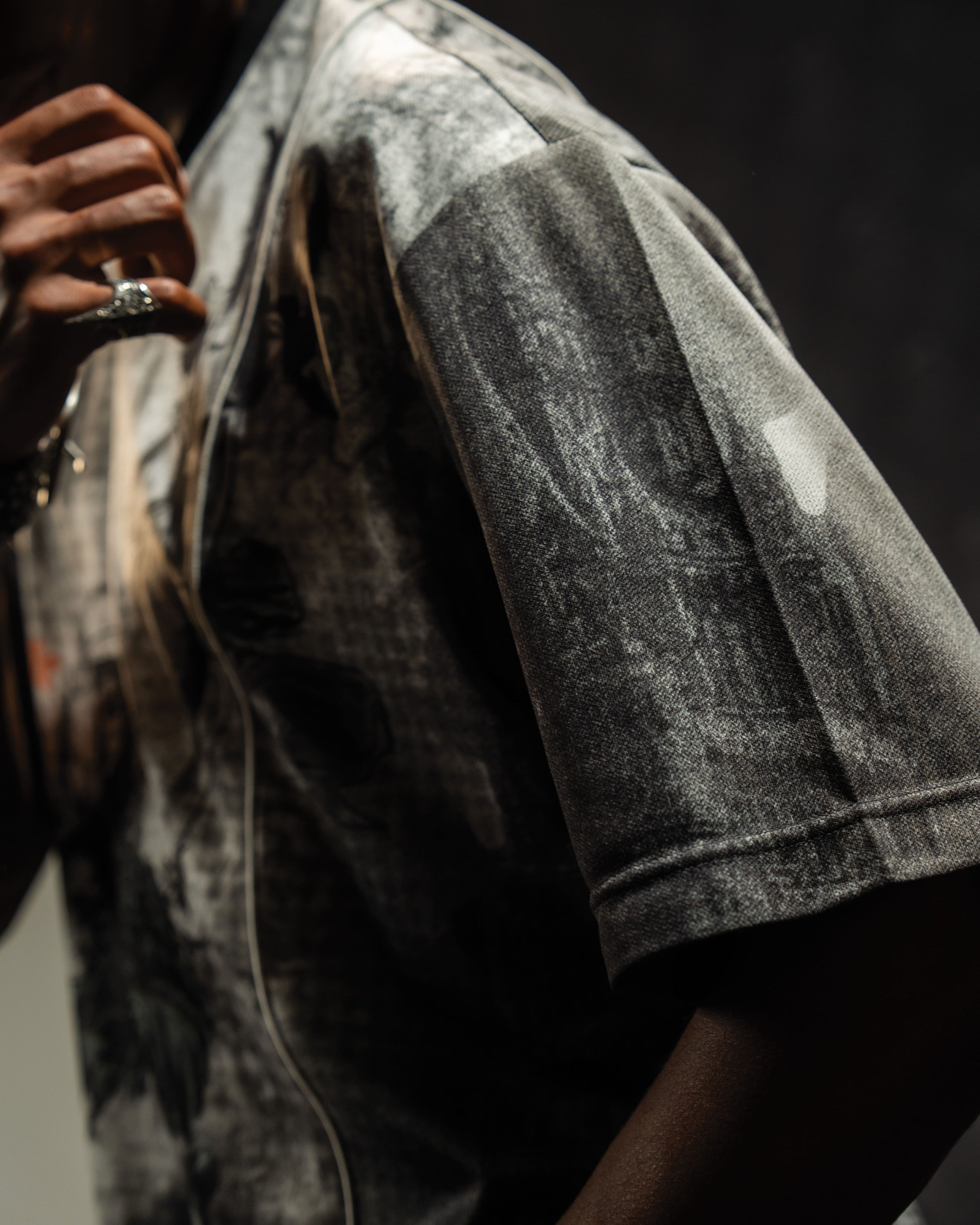 Macro shot highlighting the premium knit sleeve texture and mesh fabric finish of the graphic jersey