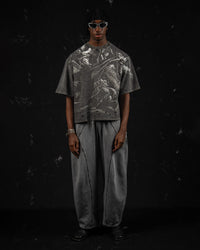 Full-length studio shot of a man styling a washed charcoal oversized graphic t-shirt with wide-leg pants