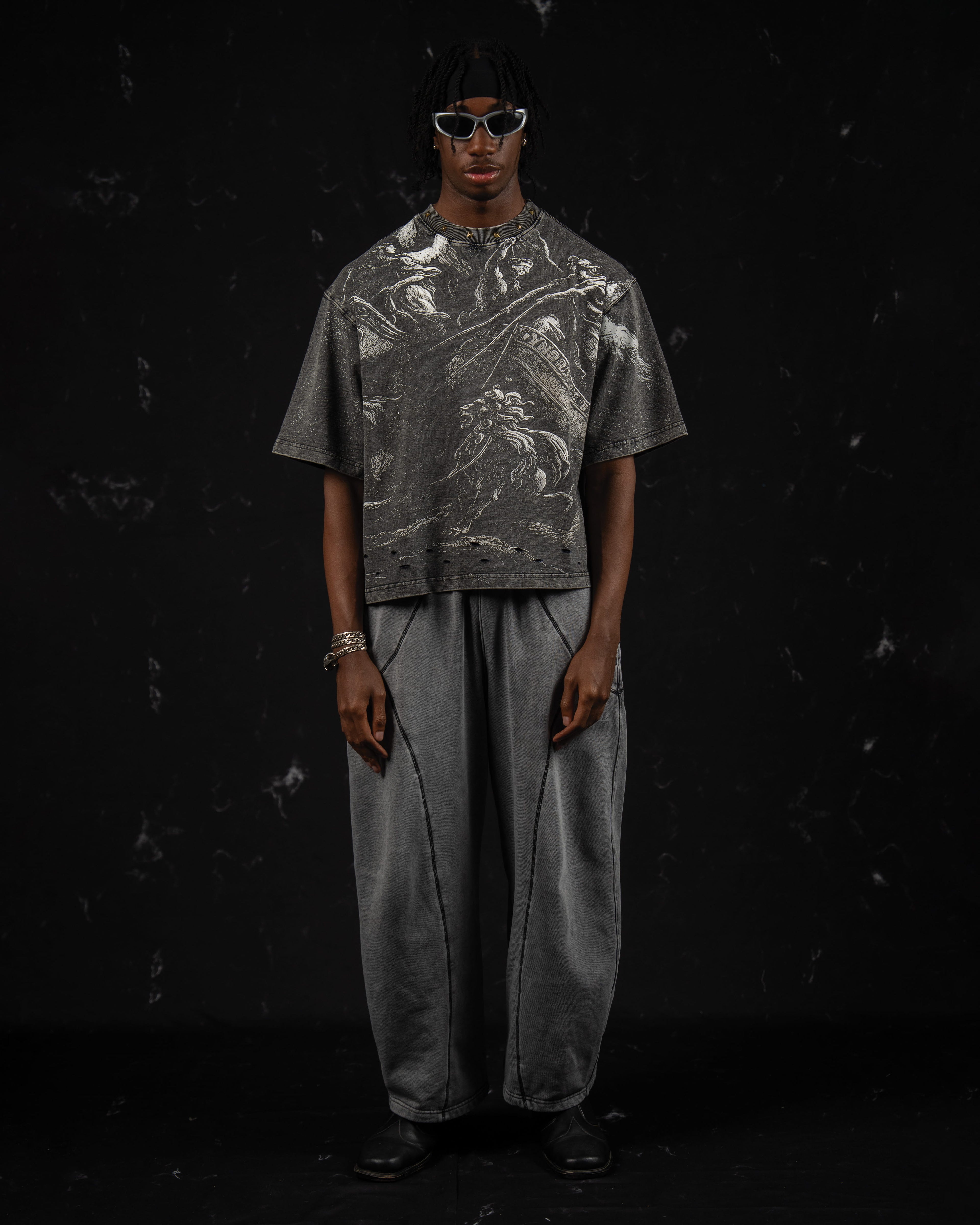 Full-length studio shot of a man styling a washed charcoal oversized graphic t-shirt with wide-leg pants