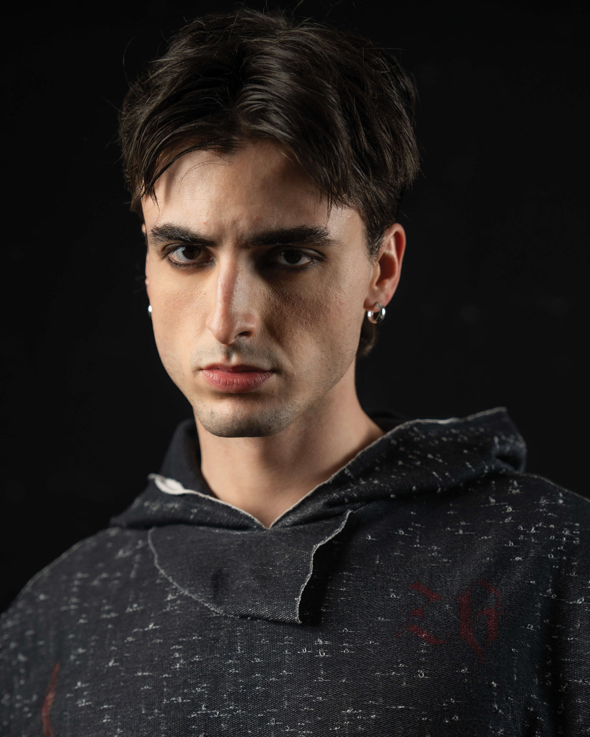 Portrait of a model wearing a washed charcoal oversized hooded graphic tee with mythic artwork
