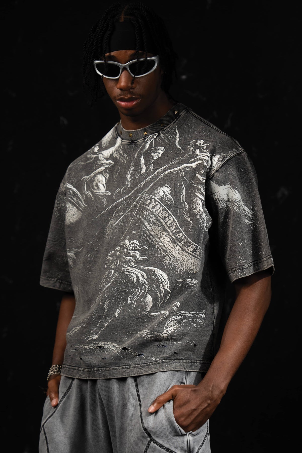 Front portrait of a man wearing a washed charcoal oversized graphic t-shirt with mythic artwork