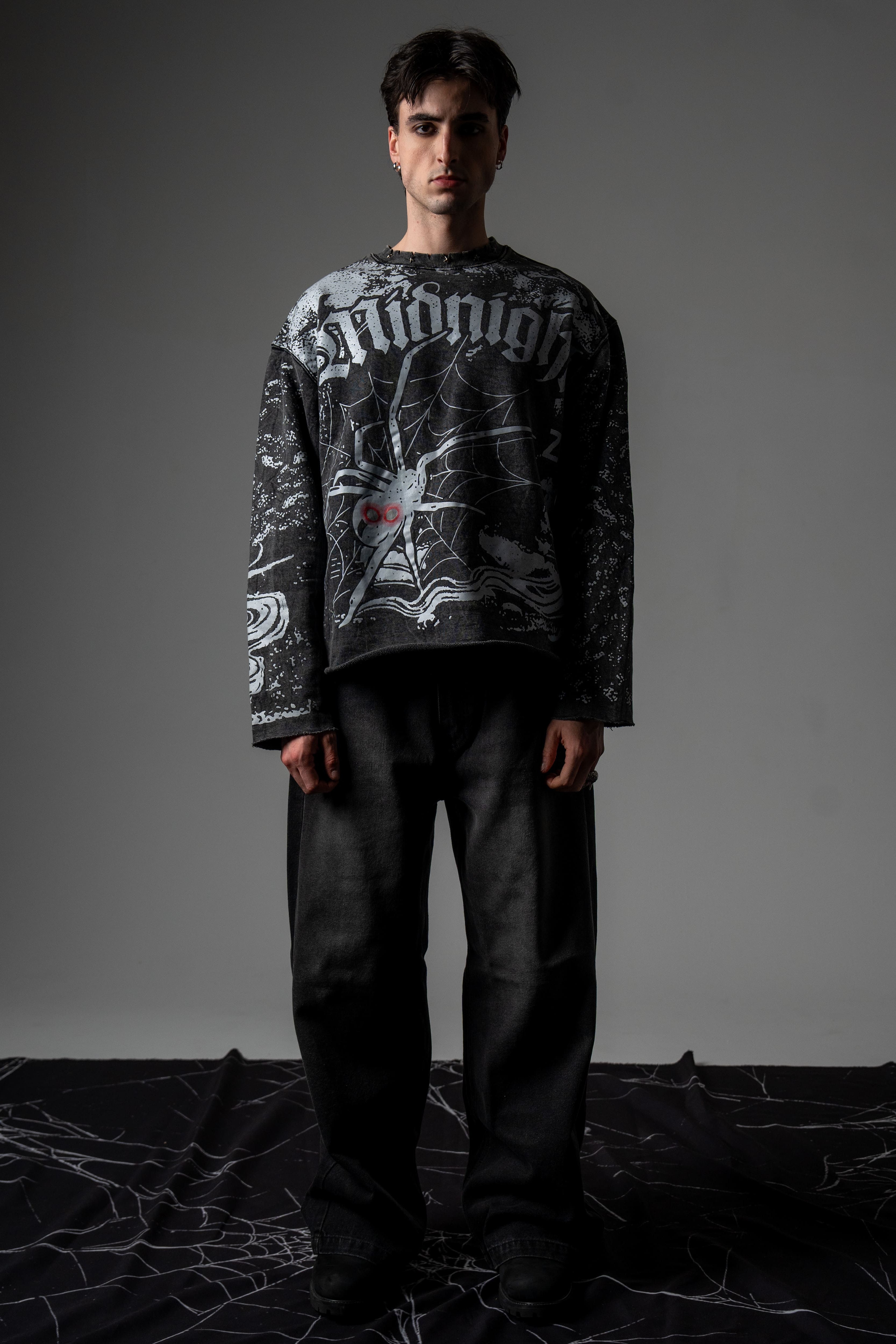 Front full-length studio portrait of a model wearing the washed charcoal SPYCRA.NODE screenprinted long sleeve tee