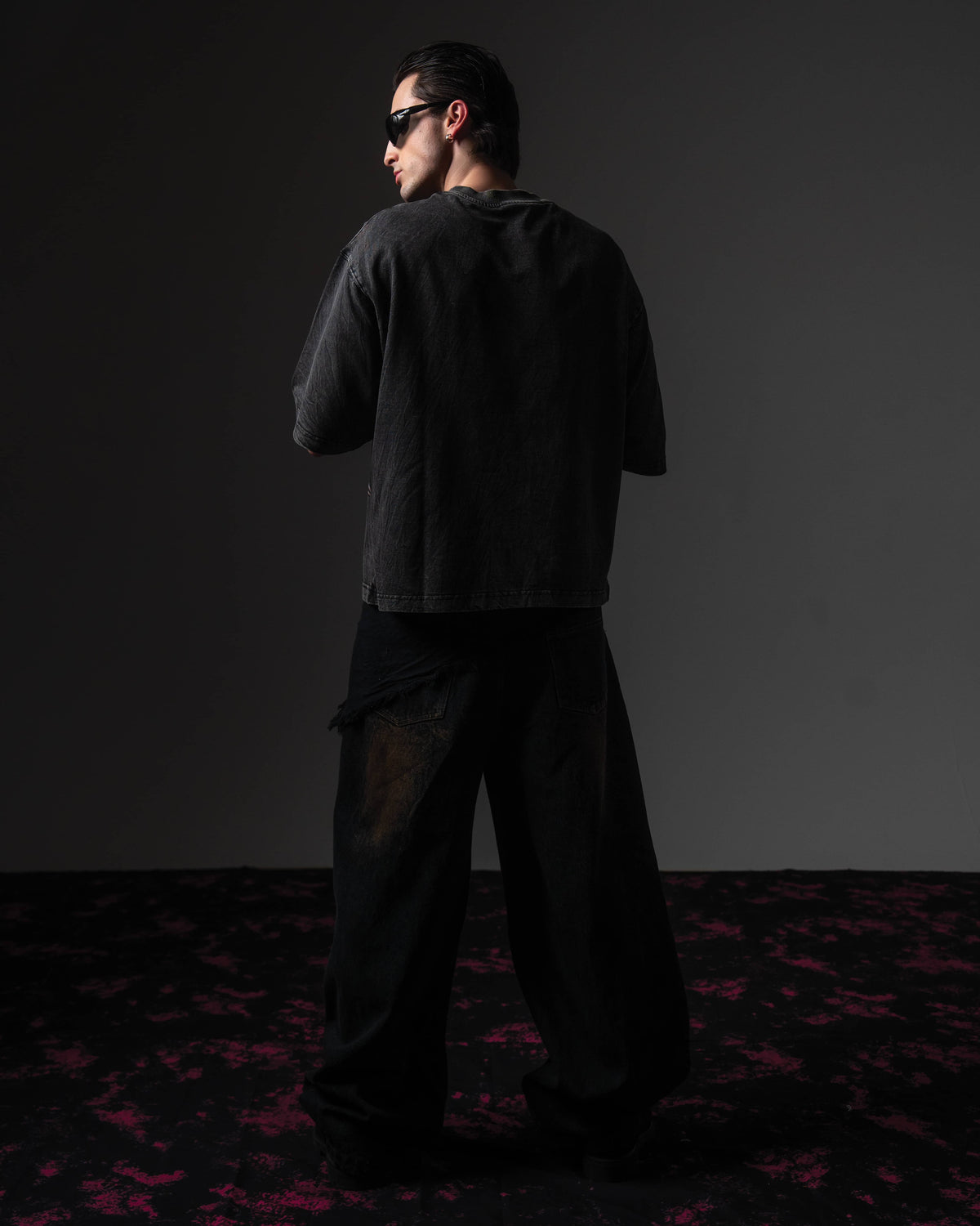 Clean back view of a man wearing an oversized black washed graphic t-shirt showing the distressed finish