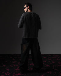 Clean back view of a man wearing an oversized black washed graphic t-shirt showing the distressed finish