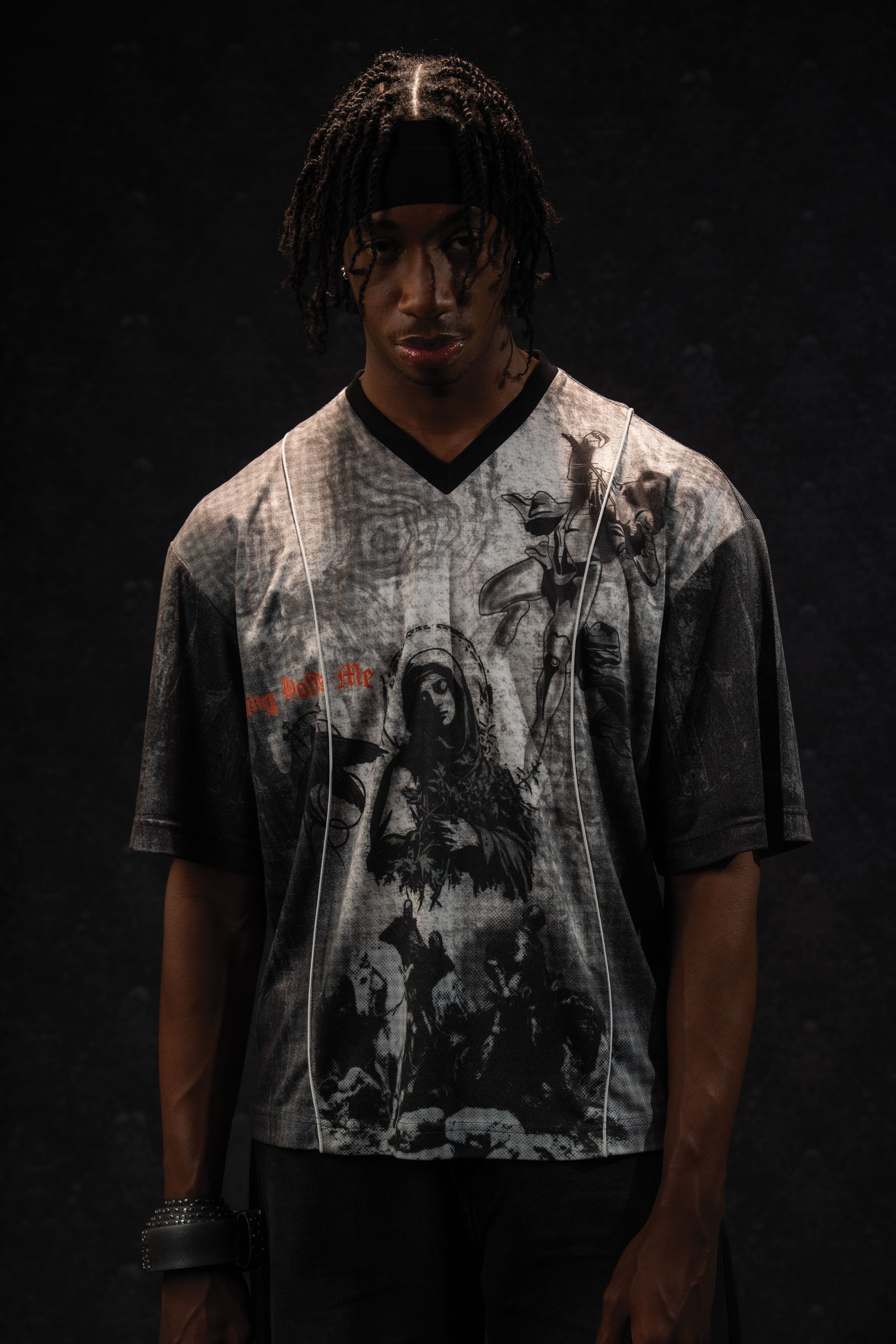 Studio portrait of a man modeling a grey and black oversized graphic jersey