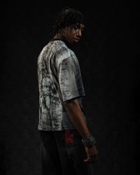 Side profile view of a man wearing a relaxed-fit grey and black oversized streetwear jersey