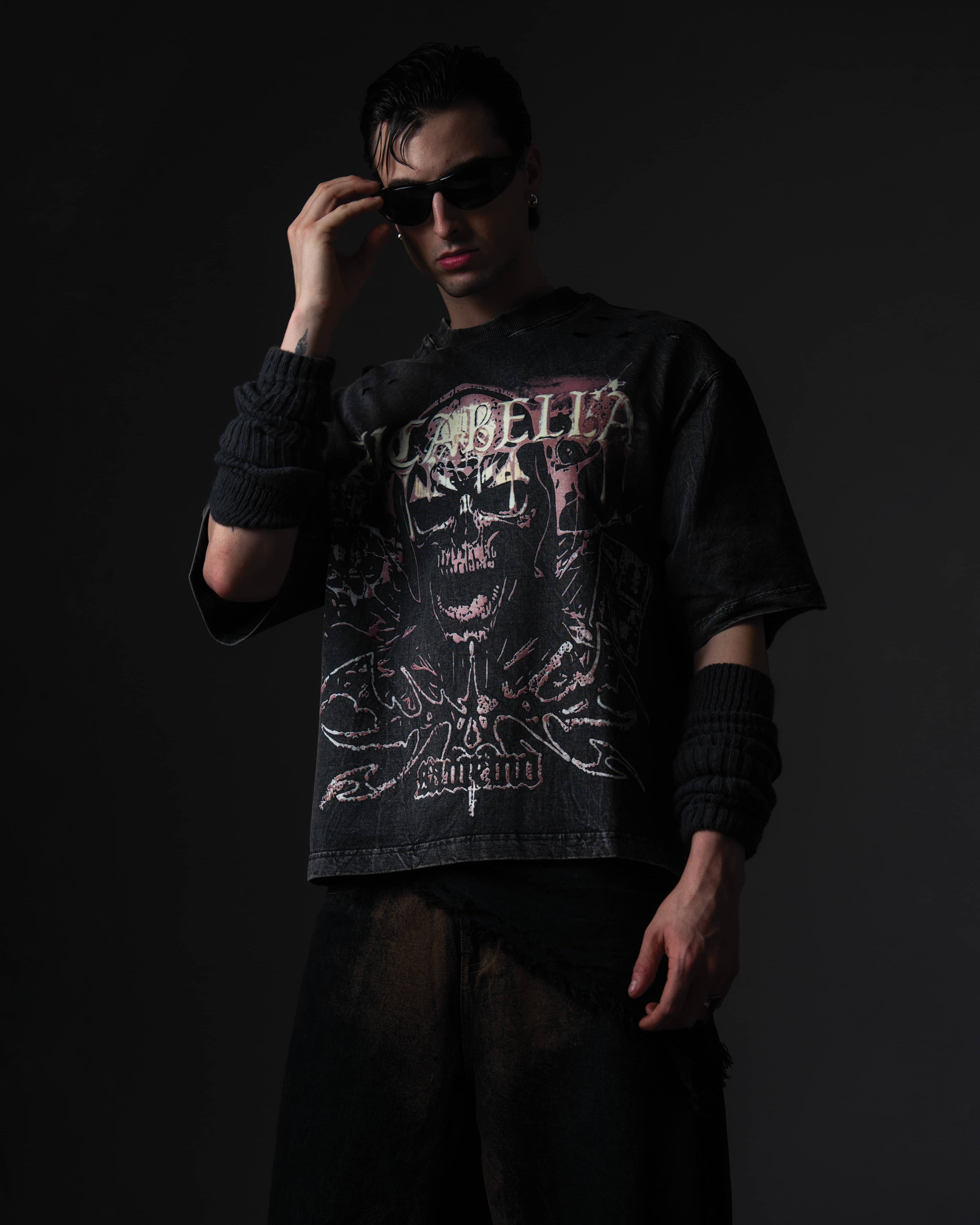 Fashion portrait of a man styling a black skull graphic t-shirt with sunglasses and arm warmers