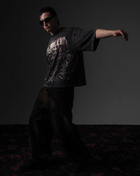 Dynamic studio action pose of a man modeling a black skull graphic t-shirt in a relaxed fit