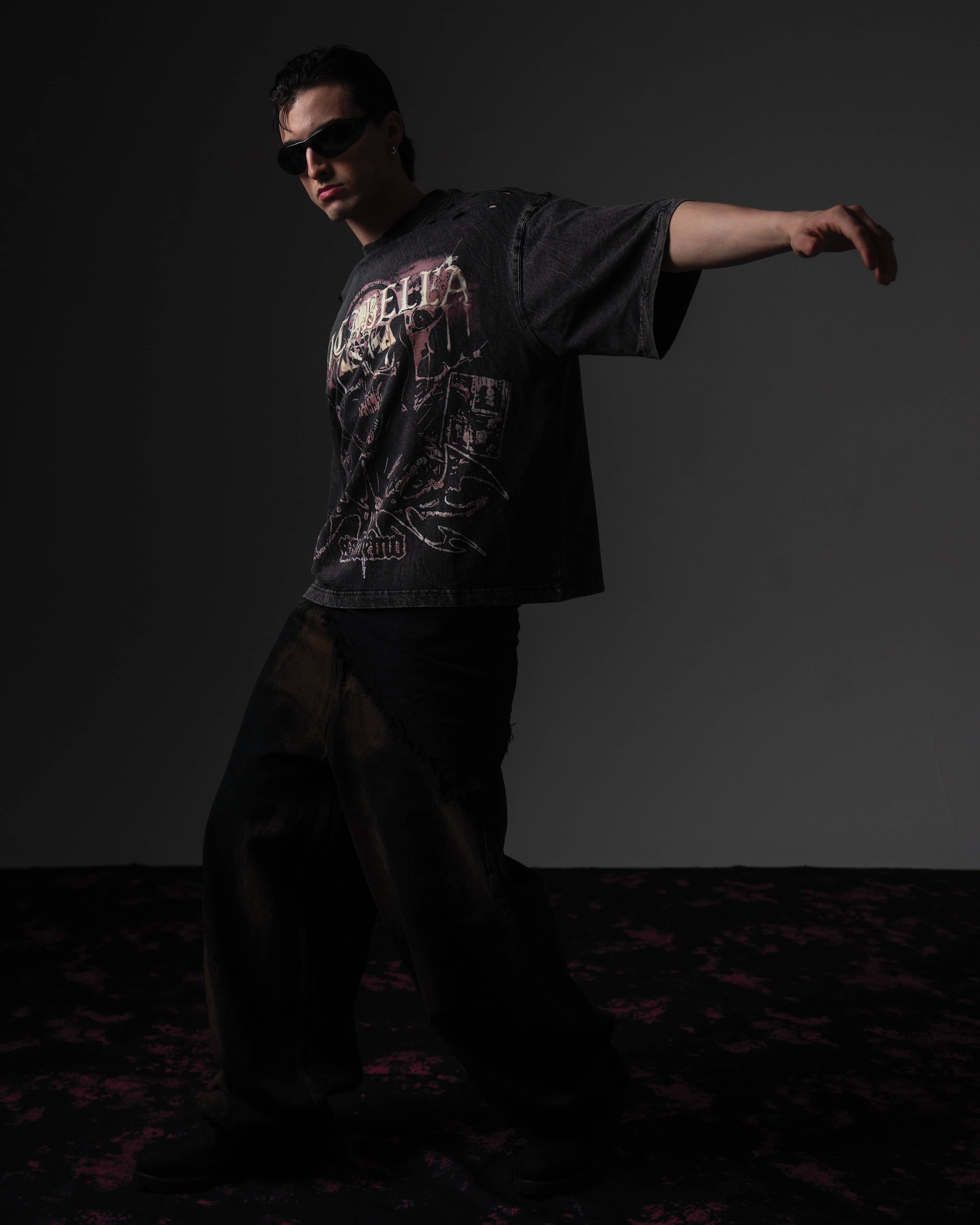 Dynamic studio action pose of a man modeling a black skull graphic t-shirt in a relaxed fit