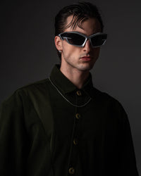 Close-up headshot portrait of a man featuring a dark olive oversized shirt