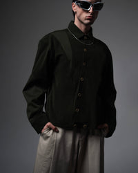 Three-quarter angle studio shot of a man wearing a dark olive oversized shirt