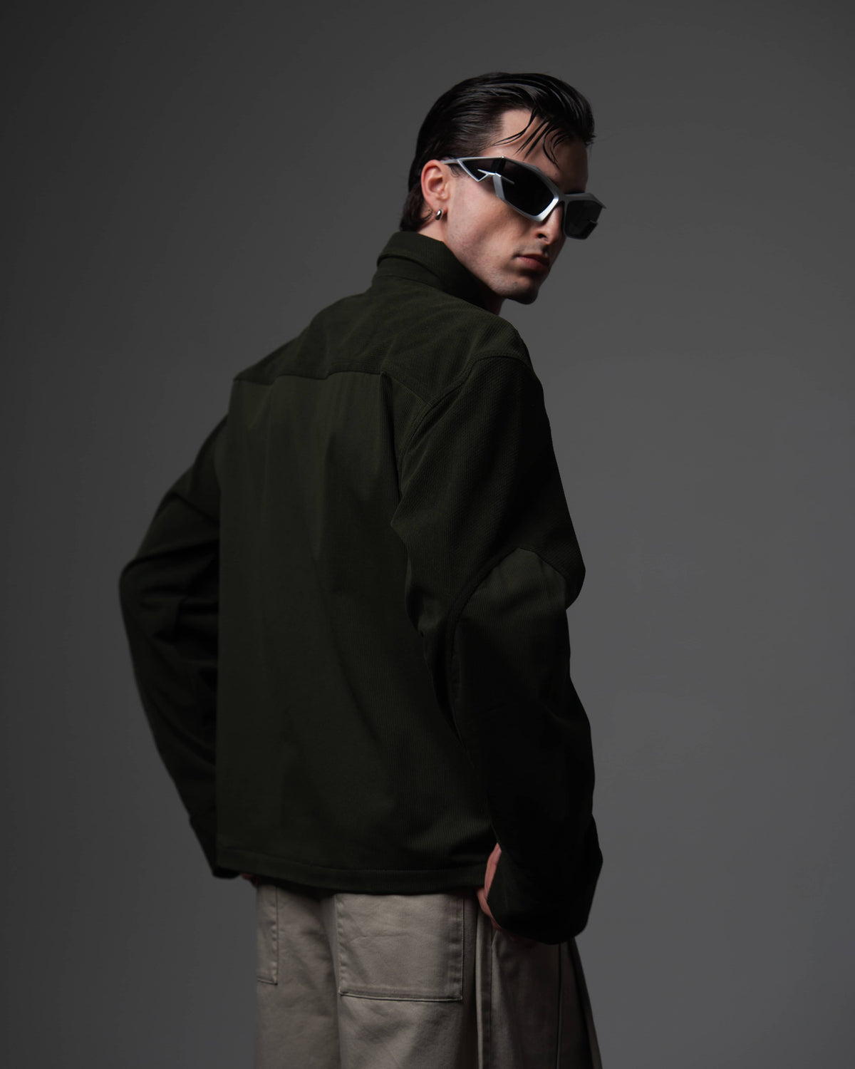 Clean back view of a man wearing an oversized textured dark olive shirt showing the drape