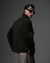 Clean back view of a man wearing an oversized textured dark olive shirt showing the drape