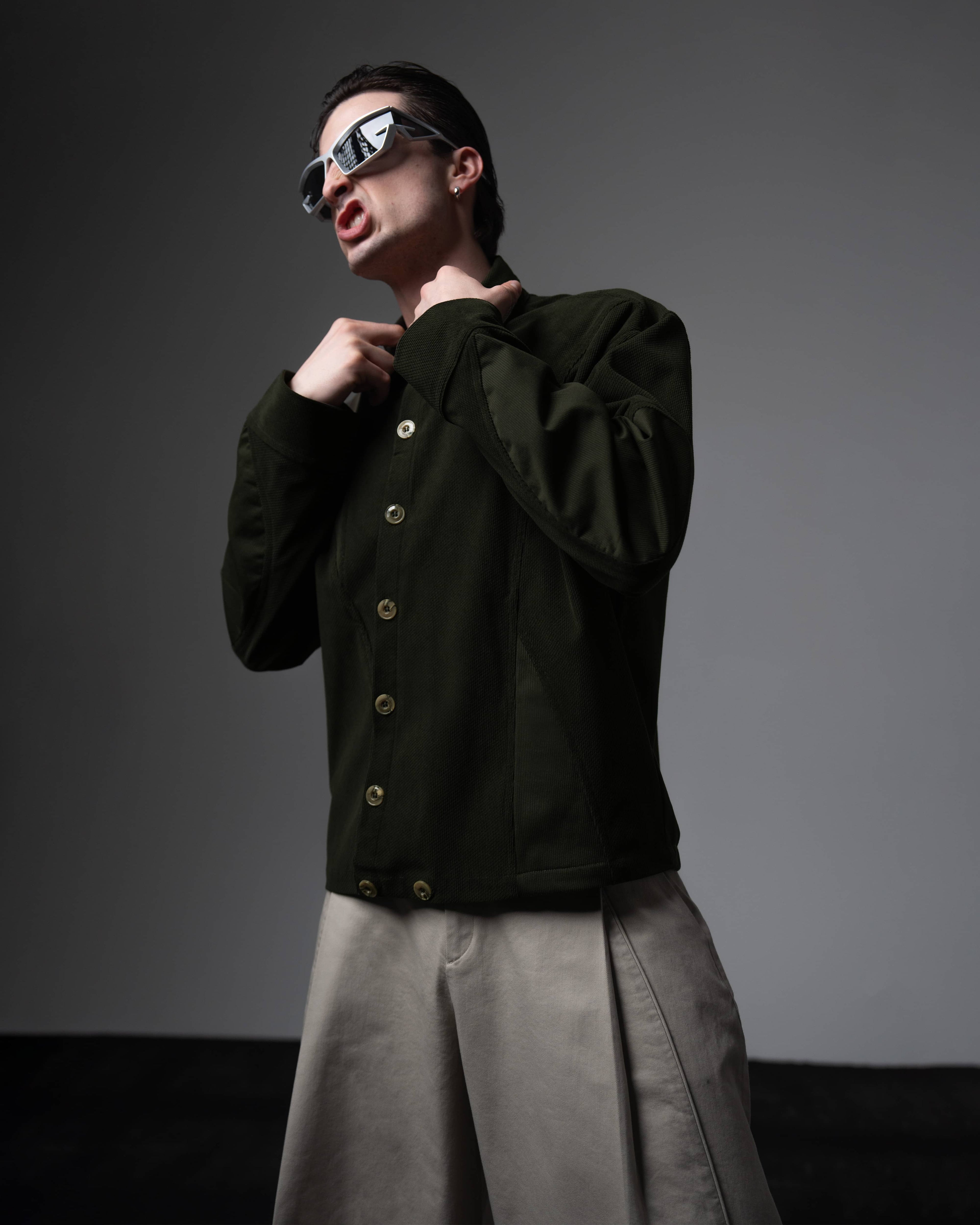 Side profile portrait of a man wearing a dark olive textured oversized shirt