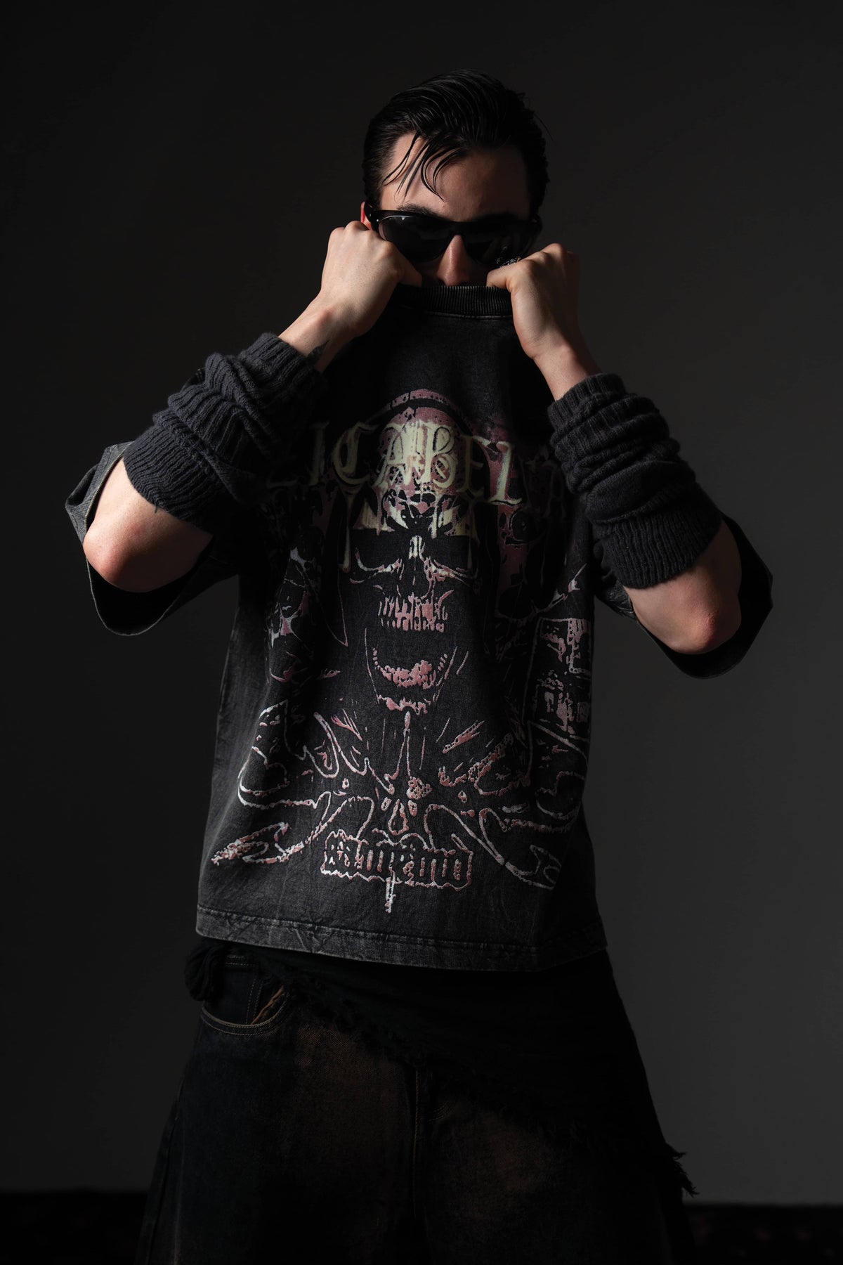 Studio pose of a man wearing a black distressed skull graphic t-shirt styled with sunglasses