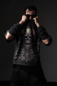 Studio pose of a man wearing a black distressed skull graphic t-shirt styled with sunglasses
