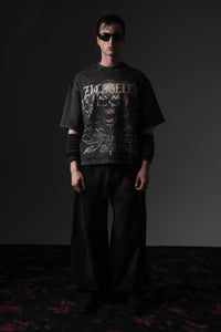 Front full-length shot of a man wearing a washed black oversized skull graphic t-shirt by Zicabella