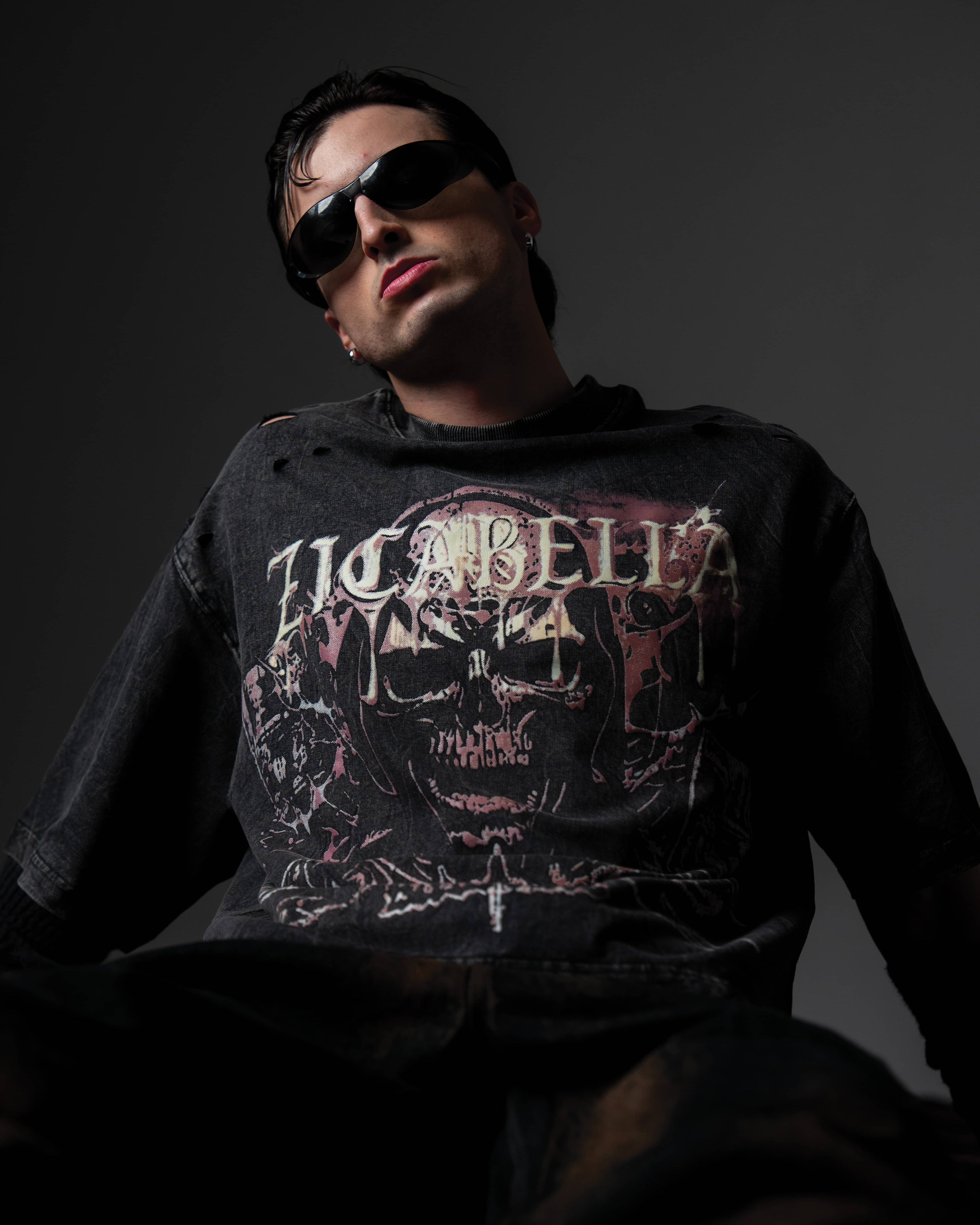 Low-angle studio shot of a man wearing a relaxed oversized washed black t-shirt with a large skull print