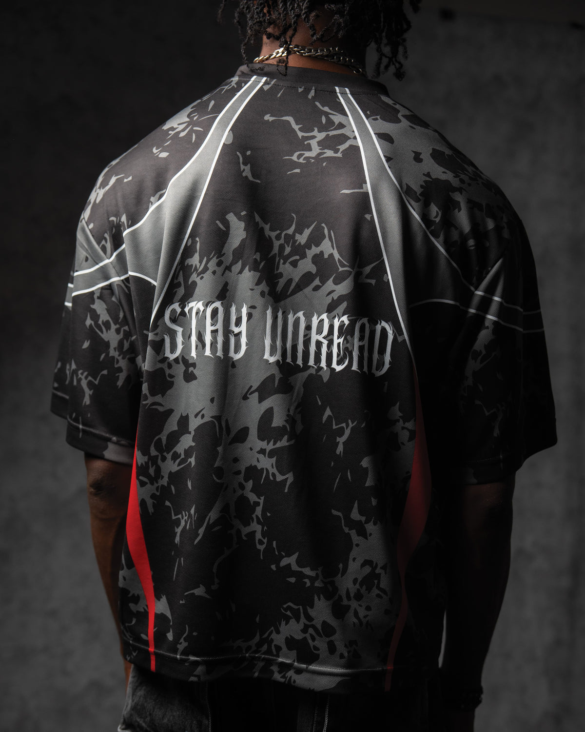 Back view of a man wearing the ZBRIX_26 streetwear jersey, highlighting the white gothic 'STAY UNREAD' back print