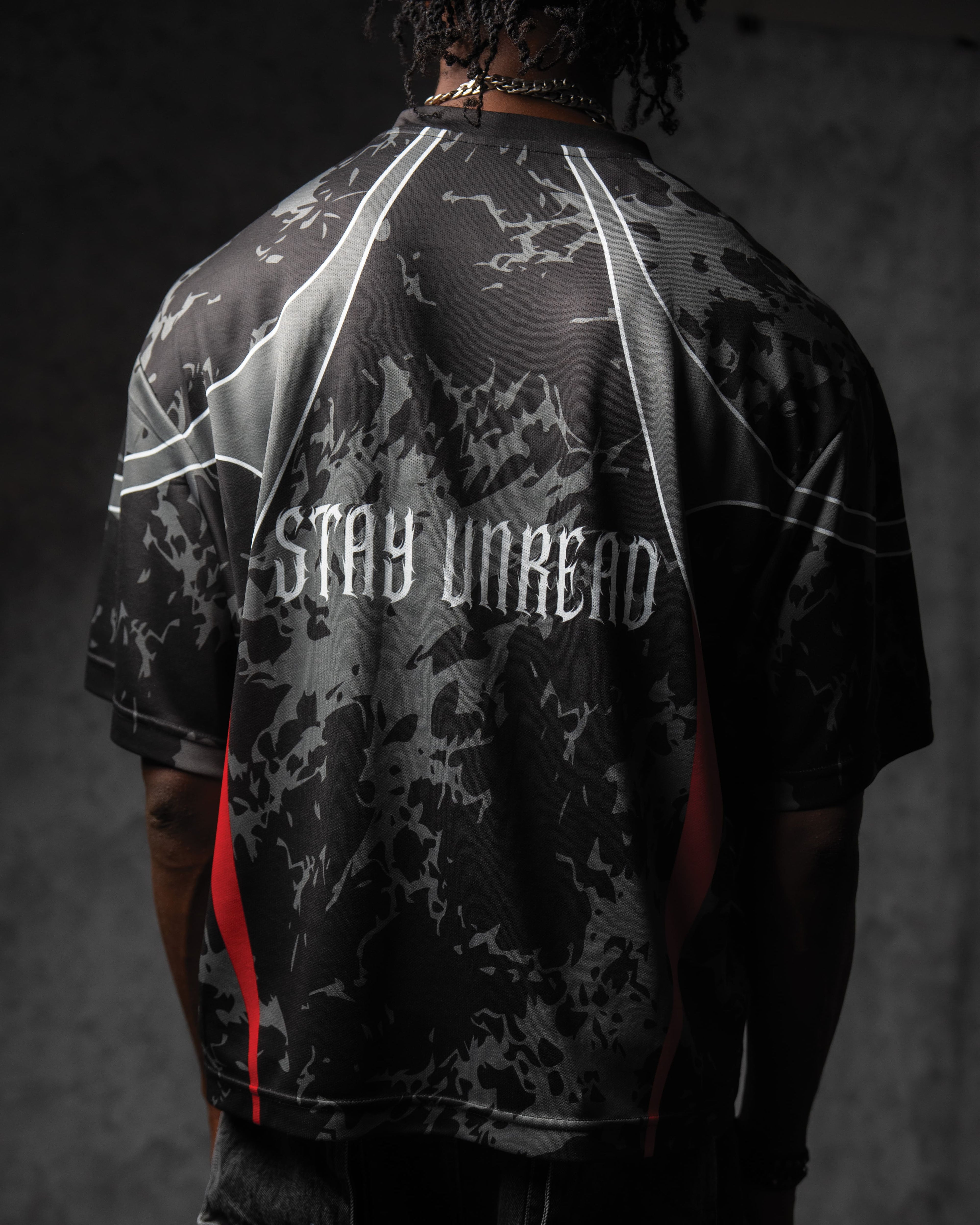 Back view of a man wearing the ZBRIX_26 streetwear jersey, highlighting the white gothic 'STAY UNREAD' back print