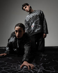 Editorial fashion portrait of models styling oversized SPYCRA.NODE screenprinted spiderweb long sleeve tees