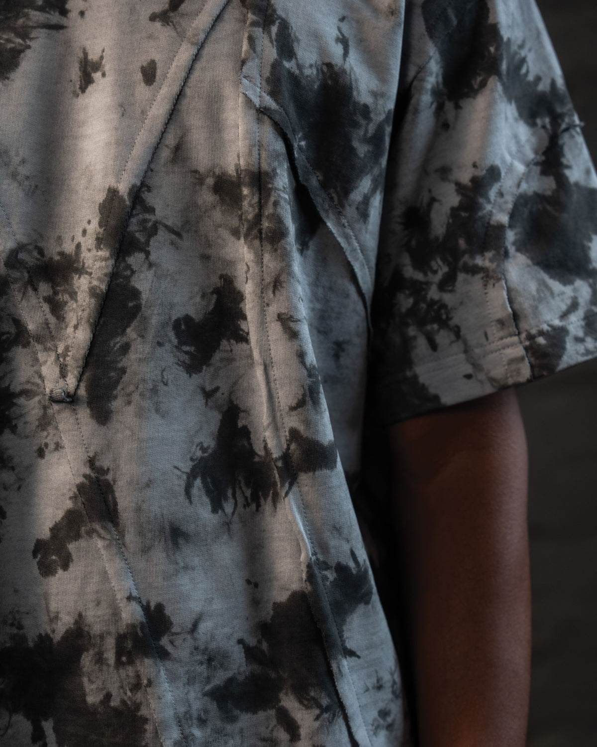 Detailed fabric texture of grey black acid wash streetwear tee with distressed stitching