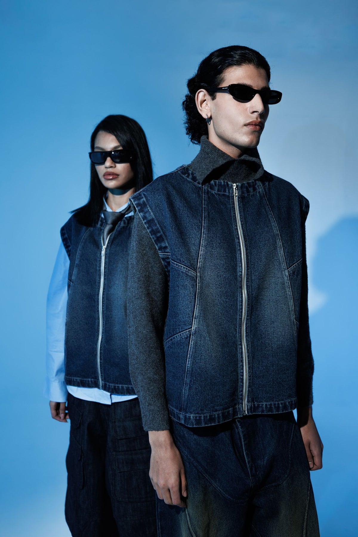 Sleeveless denim jacket worn in layered streetwear outfit for men