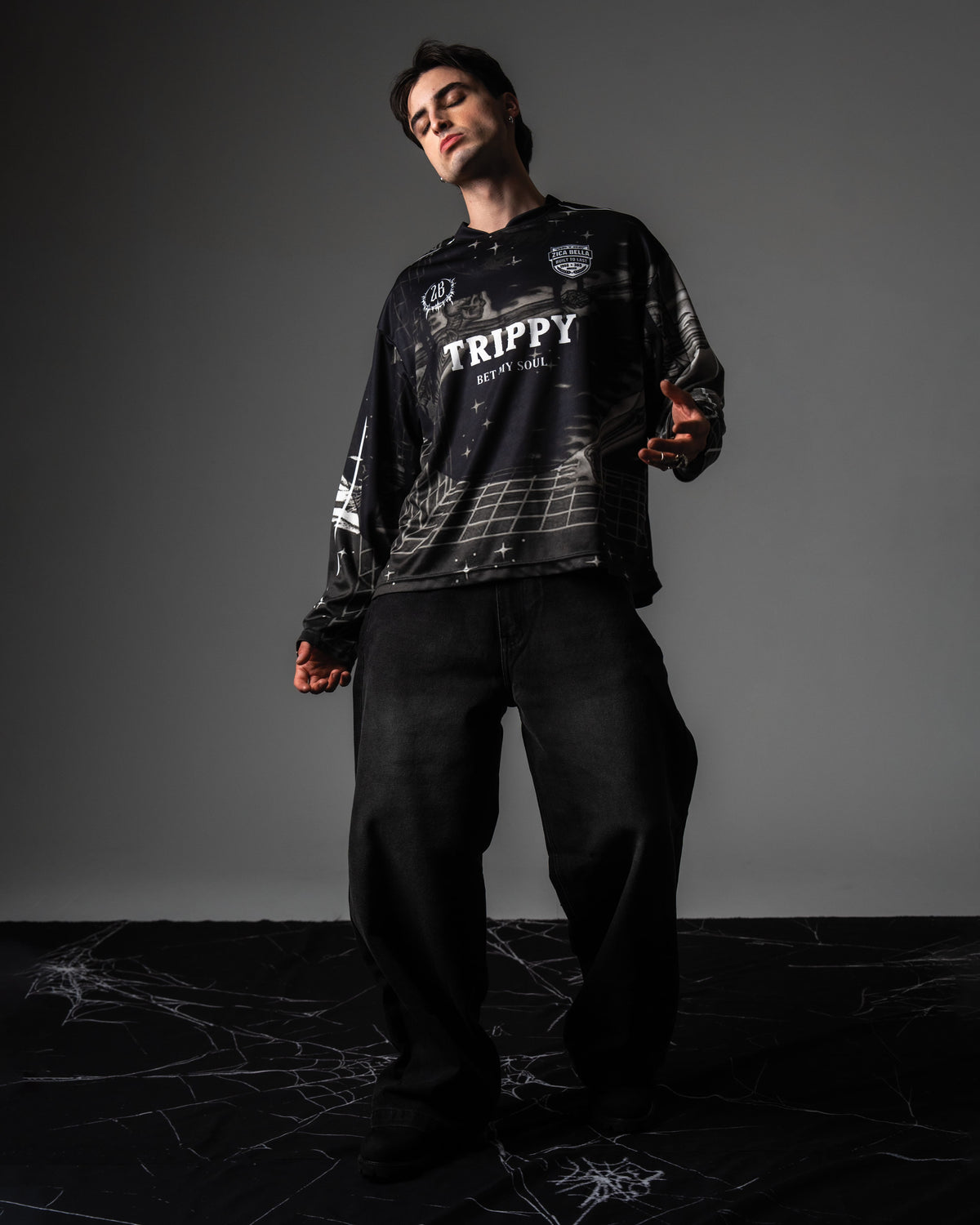 Full body studio portrait of a model wearing the TRPPY_22 oversized long sleeve jersey with black denim