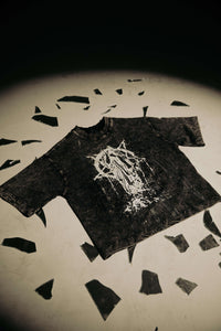 Flat lay of washed black cotton graphic t-shirt highlighting distressed streetwear design