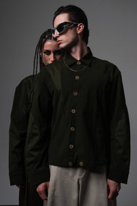 Front view of a couple posing together in matching dark olive oversized shirts