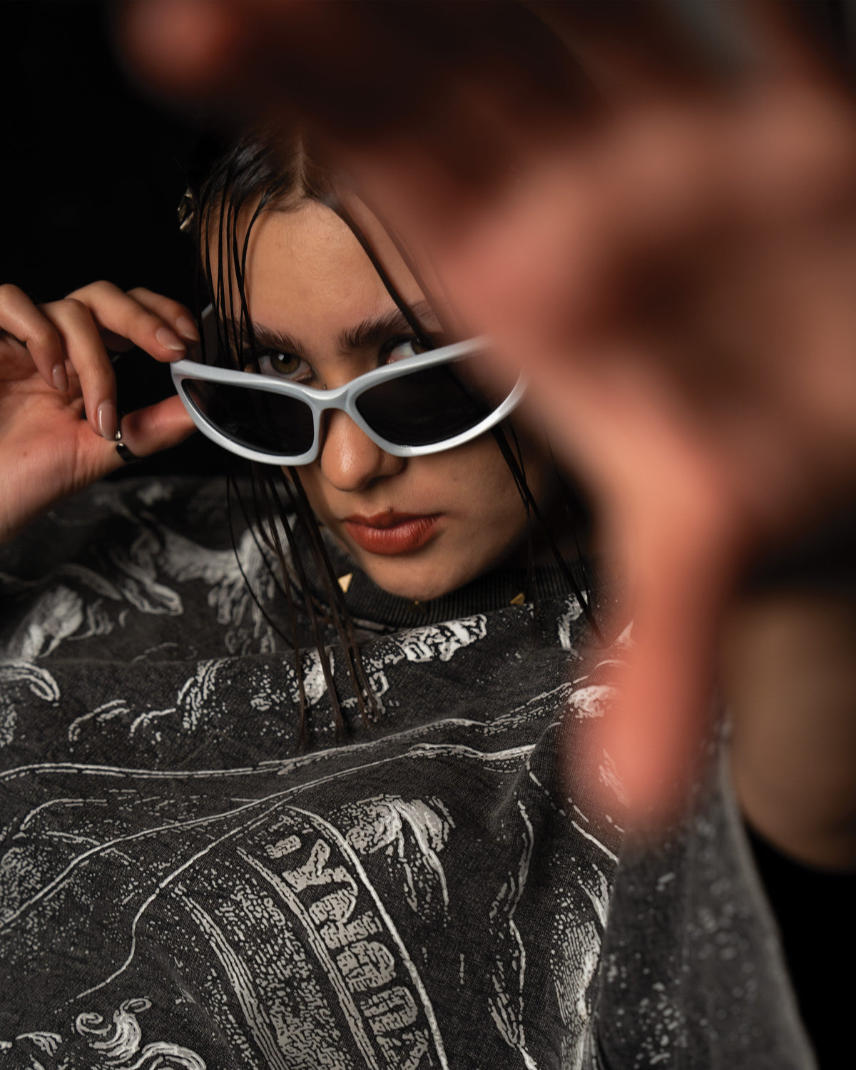 Cinematic portrait of a woman styling a washed charcoal oversized graphic t-shirt with statement sunglasses