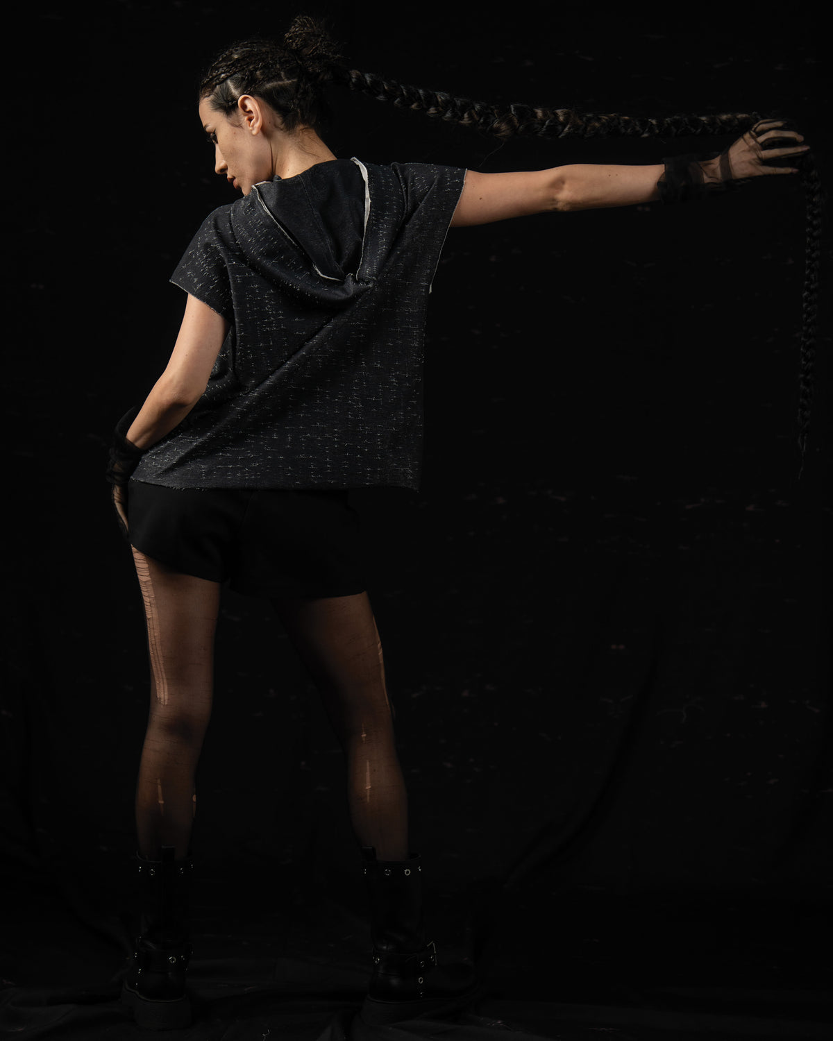 Back editorial shot of a woman wearing a washed charcoal oversized hooded graphic tee