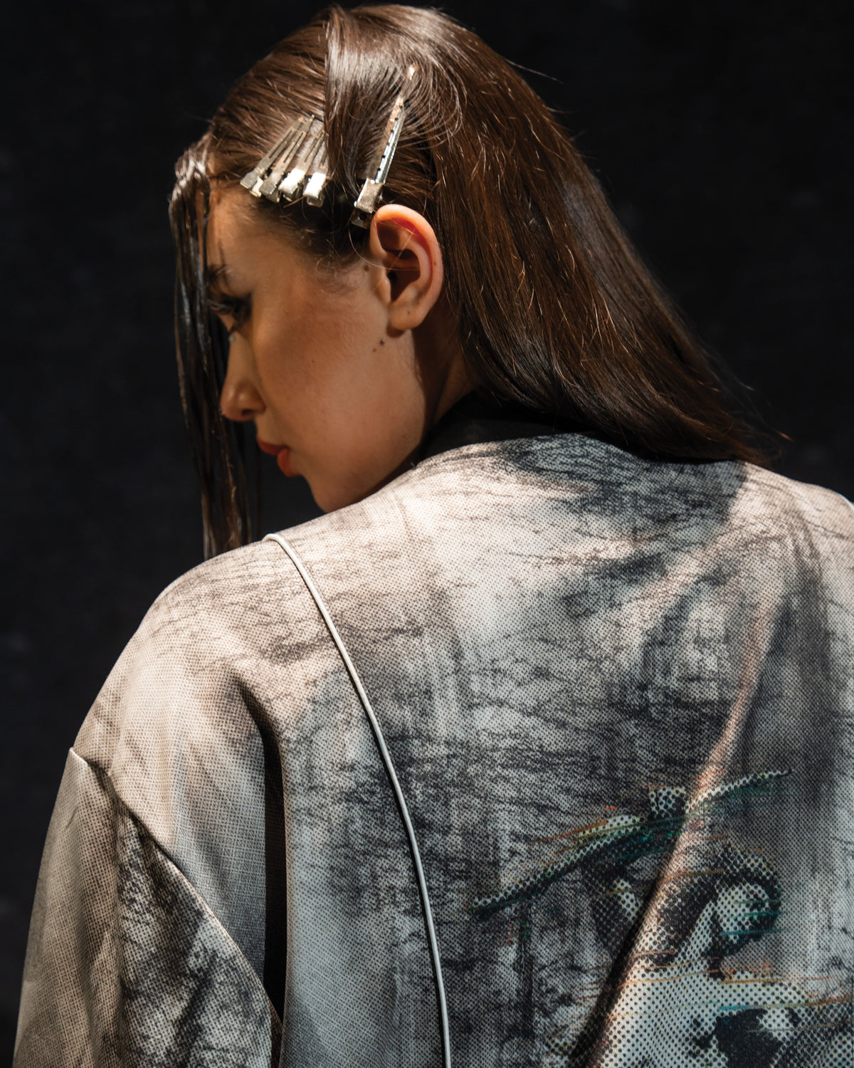 Rear portrait view of a woman showcasing the large back print on the grey and black oversized jersey
