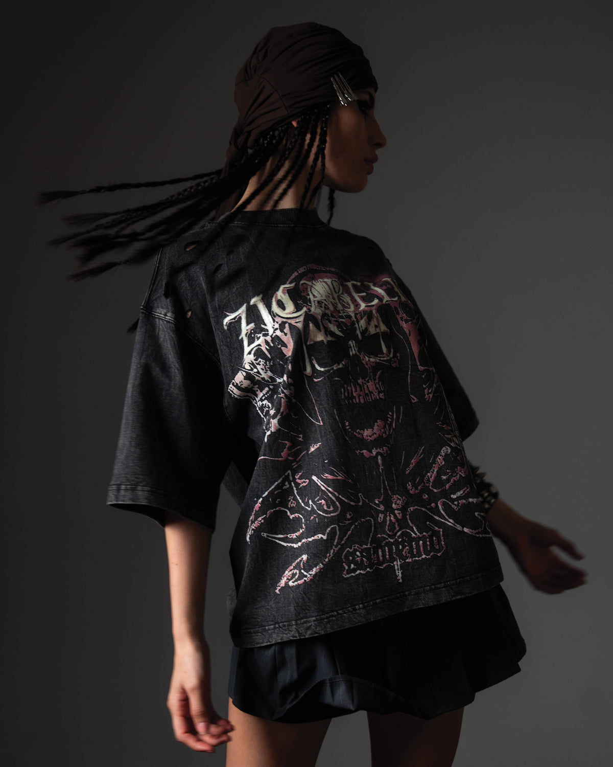 In-motion studio pose of a woman wearing a black oversized t-shirt with a premium skull print