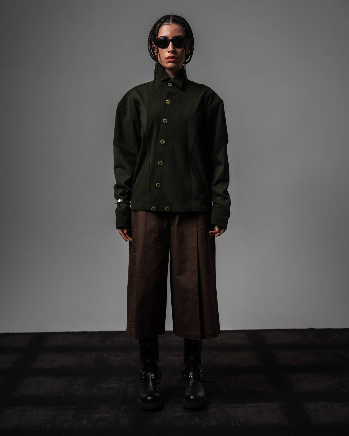 Full-length high-fashion shot of a woman wearing a dark olive oversized shirt